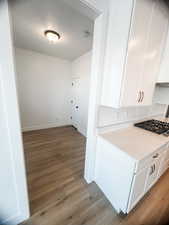 Kitchen featuring white cabinets, stainless steel gas stovetop, and light wood-type flooring