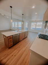 Kitchen featuring stainless steel dishwasher, light hardwood / wood-style flooring, hanging light fixtures, gas stovetop, and sink