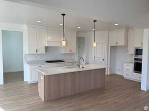 Kitchen with sink, white cabinetry, stainless steel appliances, and a kitchen island with sink