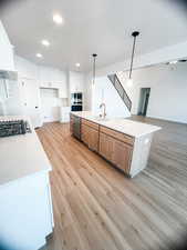 Kitchen featuring pendant lighting, a large island, white cabinetry, appliances with stainless steel finishes, and sink