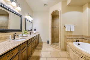 Bathroom featuring tile patterned floors, vanity, and plus walk in shower