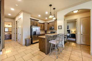 Kitchen with a kitchen bar, backsplash, light stone counters, stainless steel appliances, and a kitchen island