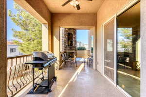 Balcony with area for grilling, ceiling fan, and an outdoor stone fireplace