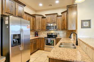 Kitchen with sink, appliances with stainless steel finishes, decorative backsplash, light tile patterned floors, and ornamental molding