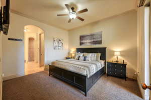 Bedroom with carpet, ceiling fan, ornamental molding, and ensuite bath