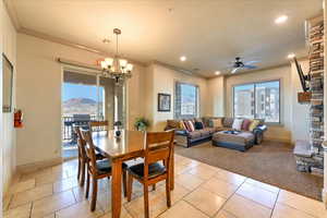 Dining space featuring a mountain view, a stone fireplace, ornamental molding, and ceiling fan with notable chandelier