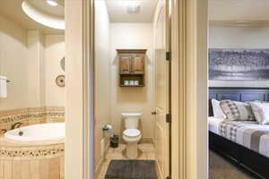 Bathroom featuring tile patterned flooring, toilet, and tiled bath