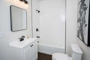 Full bathroom with hardwood / wood-style flooring, vanity, shower / bath combination, and toilet