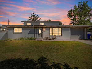 View of front facade with a lawn, a garage, and a patio