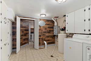 Laundry room with cabinets, independent washer and dryer, and wooden walls