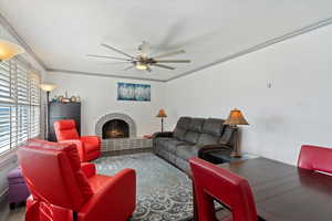 Living room with ceiling fan, a fireplace, and ornamental molding