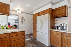 Kitchen with crown molding, ceiling fan, a fireplace, white fridge, and dark hardwood / wood-style flooring