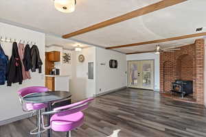 Dining area featuring beam ceiling, a textured ceiling, electric panel, and dark wood-type flooring