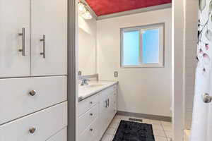 Bathroom featuring tile patterned floors, crown molding, and vanity