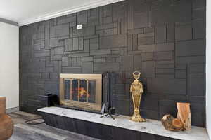 Interior details featuring wood-type flooring, a large fireplace, and ornamental molding