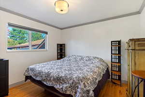 Bedroom featuring hardwood / wood-style flooring and ornamental molding