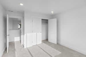 Unfurnished bedroom with light carpet and a closet