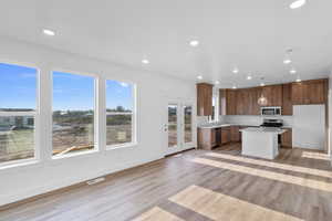 Kitchen featuring appliances with stainless steel finishes, a kitchen island, pendant lighting, and light hardwood / wood-style floors