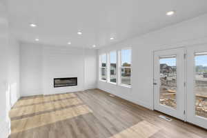 Unfurnished living room with a fireplace, a healthy amount of sunlight, and light hardwood / wood-style flooring