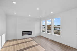 Unfurnished living room with a large fireplace and light hardwood / wood-style flooring