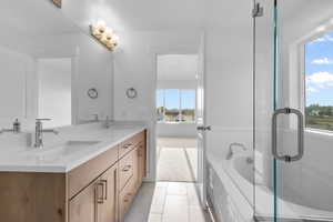 Bathroom featuring tile patterned flooring, vanity, and shower with separate bathtub