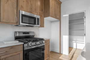 Kitchen featuring appliances with stainless steel finishes, backsplash, and light hardwood / wood-style floors