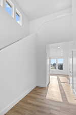 Additional living space with a towering ceiling and light hardwood / wood-style flooring