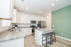 Kitchen with sink, a center island, a breakfast bar area, white cabinets, and appliances with stainless steel finishes