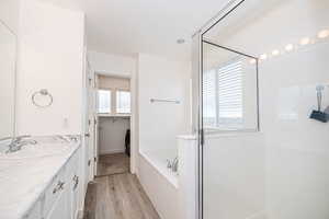 Primary Bathroom featuring vanity, shower with separate bathtub, and hardwood / wood-style flooring