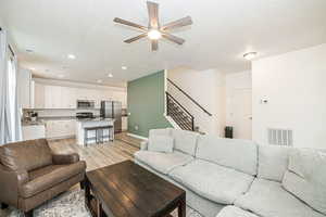 Living room with ceiling fan, sink, a textured ceiling, and light wood-type flooring