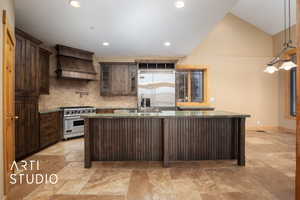 Kitchen featuring high quality appliances, a kitchen island with sink, decorative backsplash, dark brown cabinets, and custom range hood