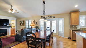 Dining area featuring a tile fireplace, light wood-type flooring, ceiling fan, and lofted ceiling