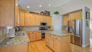 Kitchen with tasteful backsplash, stainless steel appliances, sink, a center island, and lofted ceiling