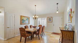 Tiled dining space featuring a chandelier and vaulted ceiling