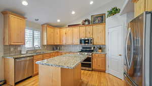 Kitchen featuring a center island, sink, stainless steel appliances, gas range with double ovens, and vaulted ceiling