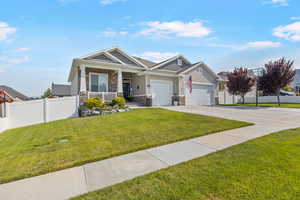 View of front of property featuring a porch, a garage, and a front lawn