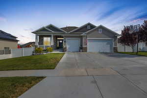 View of front facade featuring covered porch, a yard, and a garage