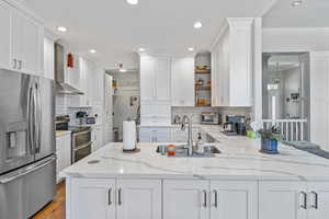 Kitchen featuring white cabinets, light stone counters, sink, and appliances with stainless steel finishes