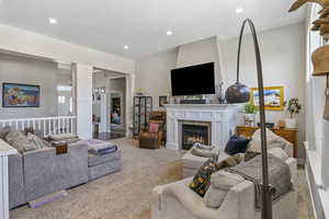 Living room with carpet, ornate columns, and a tiled fireplace