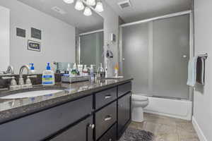 Full bathroom featuring vanity, toilet, and enclosed tub / shower combo