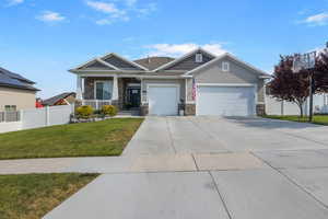 View of front of home featuring covered porch, a front yard, and a garage