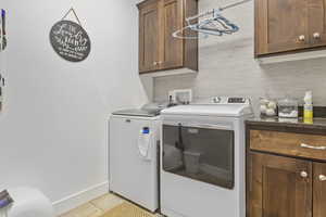 Washroom with cabinets, independent washer and dryer, and light tile patterned floors