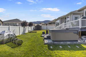 View of yard featuring a mountain view, a hot tub, and a storage shed