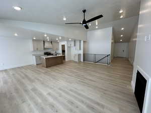 Unfurnished living room with light wood-type flooring, lofted ceiling, a textured ceiling, and ceiling fan