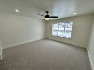 Carpeted empty room with ceiling fan and a textured ceiling