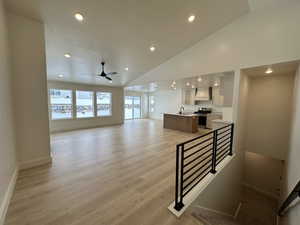 Living room featuring ceiling fan, light hardwood / wood-style flooring, sink, and high vaulted ceiling