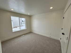 Carpeted spare room with a textured ceiling