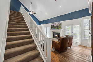 Stairway featuring french doors, vaulted ceiling, ceiling fan, a fireplace, and wood-type flooring