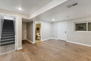 Basement with light hardwood / wood-style floors and a textured ceiling