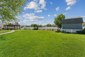 View of yard with a pergola and a storage unit